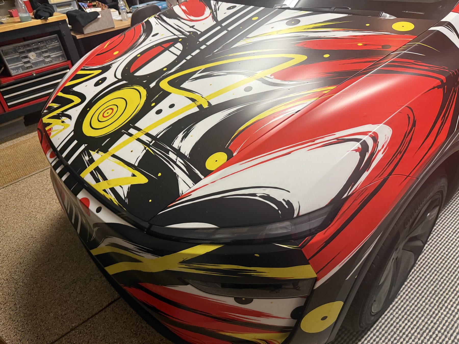 Susan Fielder presenting the red, white, yellow and black Moving Art tribute wrap in the workshop
